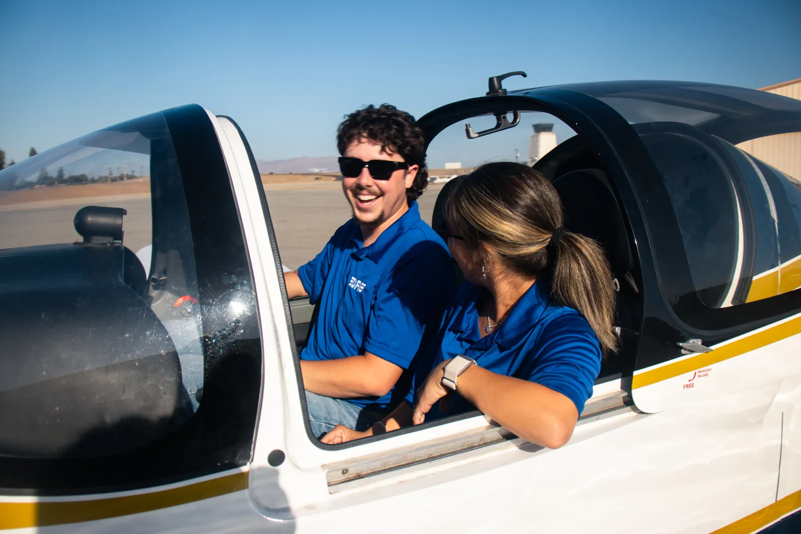 An instructor and a student laughing in the cockpit before a lesson