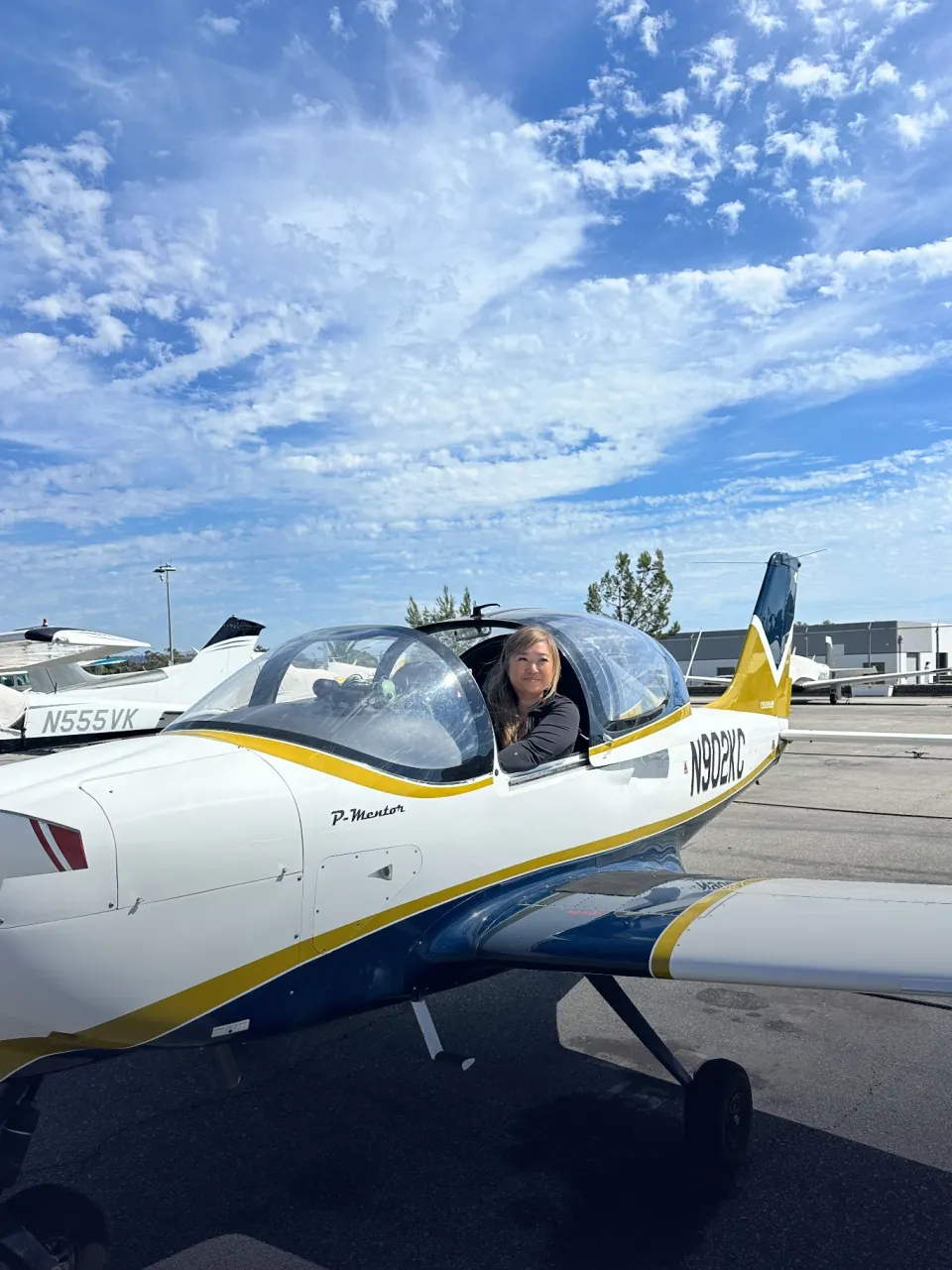 A student smiling from the cockpit of a P-Mentor