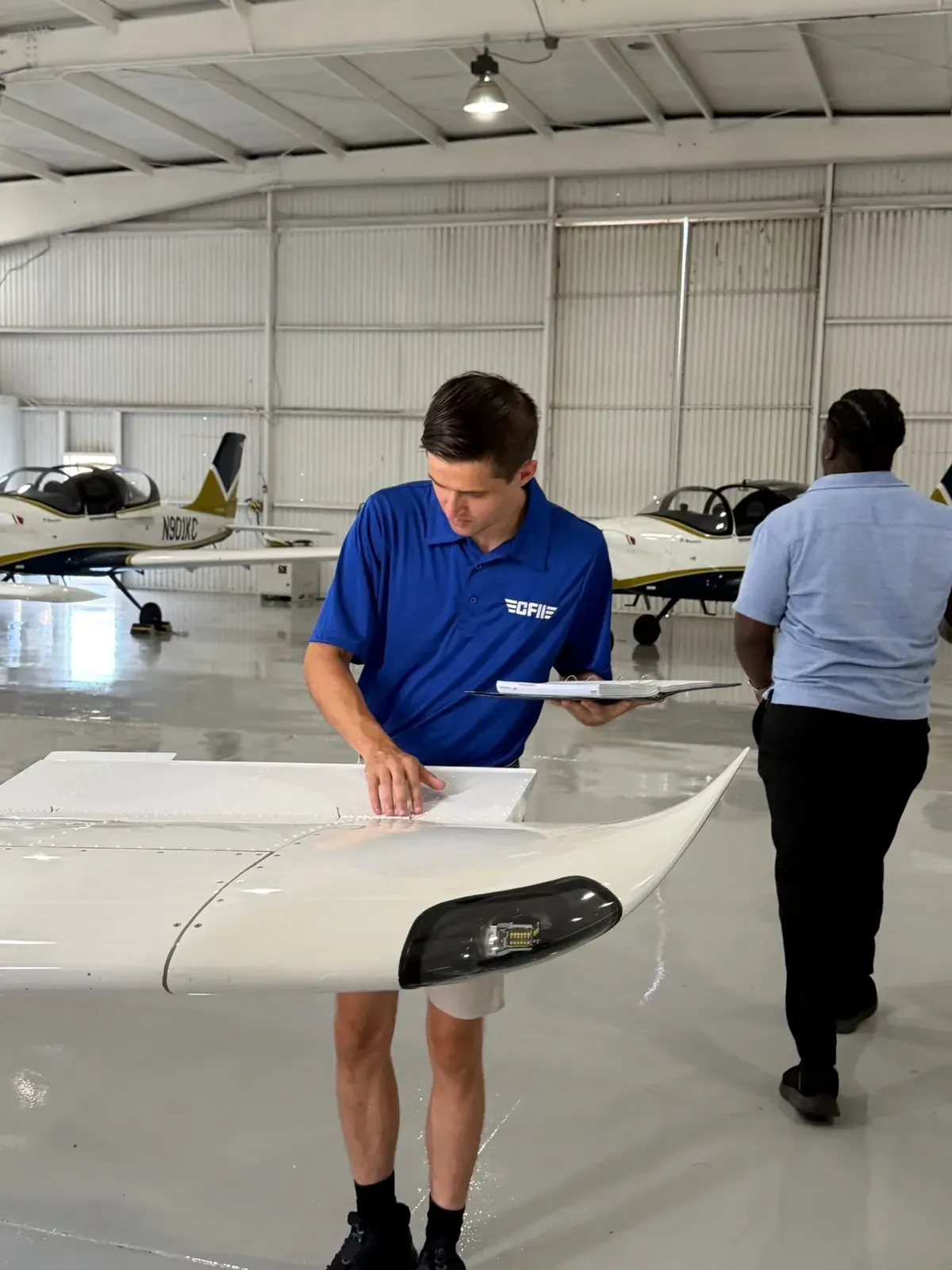 A CFII instructor briefing a student over the wing of a P-Mentor