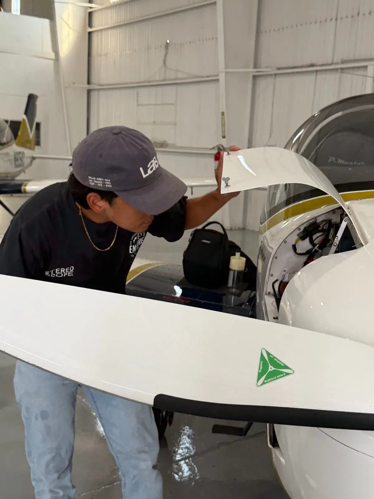 A student checking the engine bay of a P-Mentor during preflight in Riverside