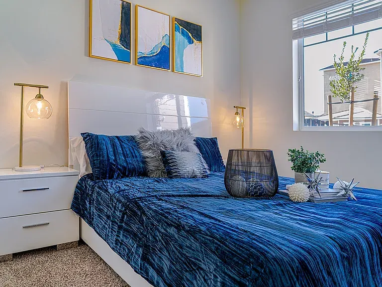 A furnished bedroom in a Turtle Creek apartment, with a window onto the neighborhood